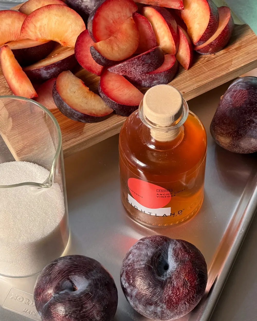 Brightland Ember chili vinegar on a tray with sliced plums